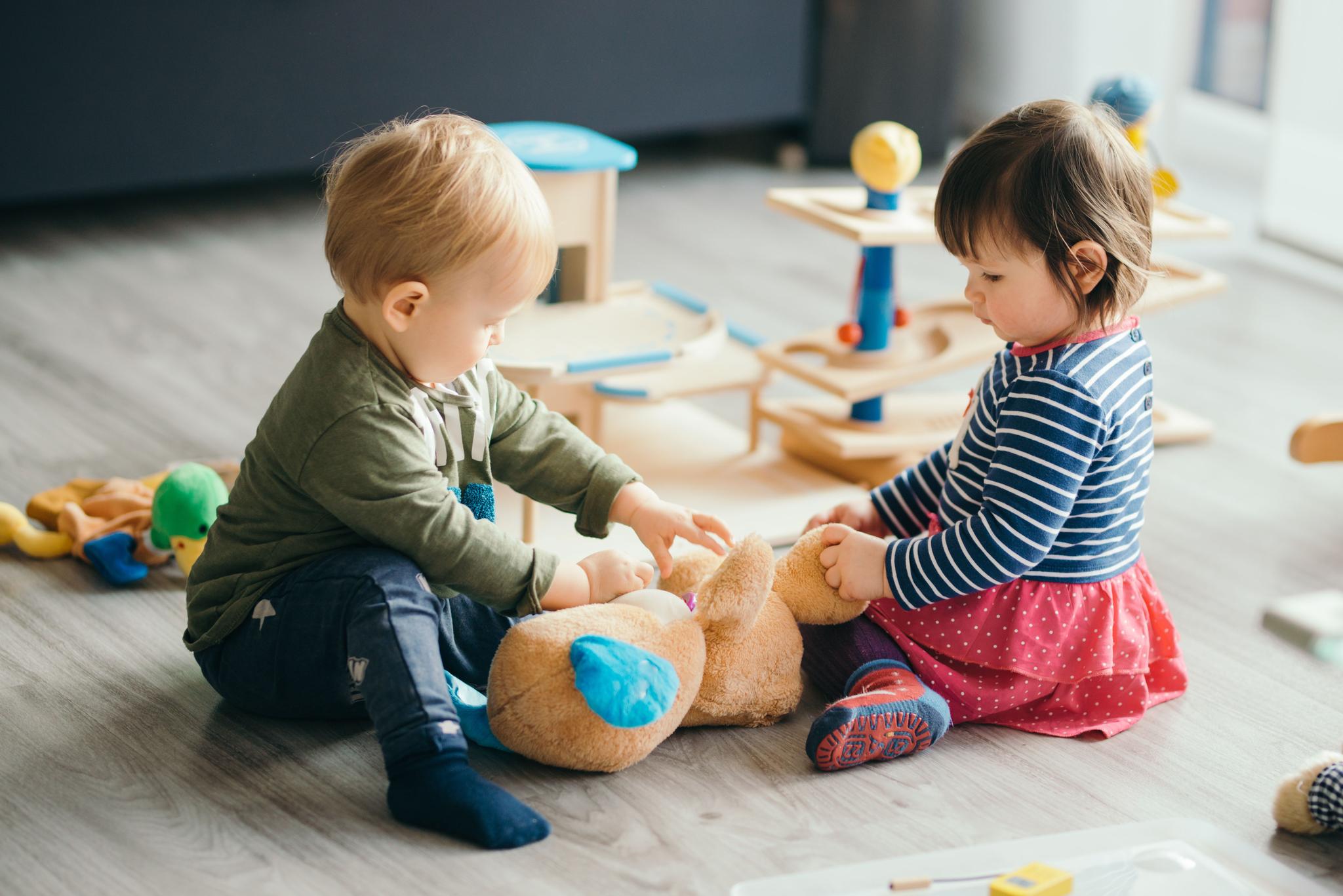 a boy and a girl are sitting on the floor playing with toys .