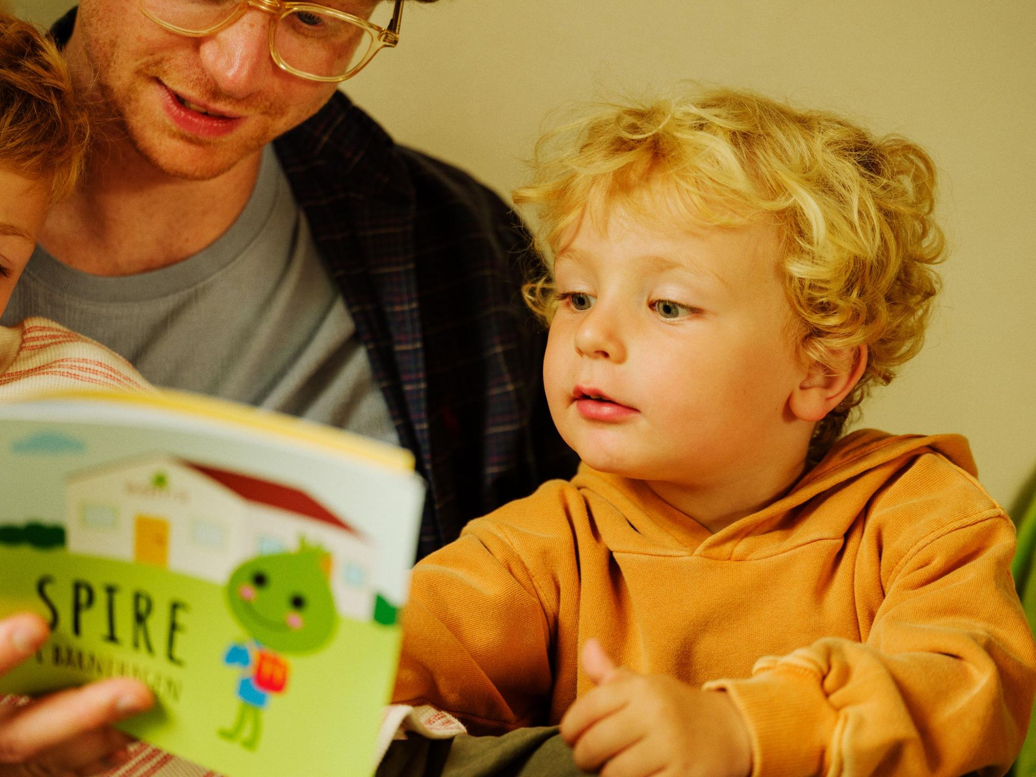 a man is reading a book to a young boy .