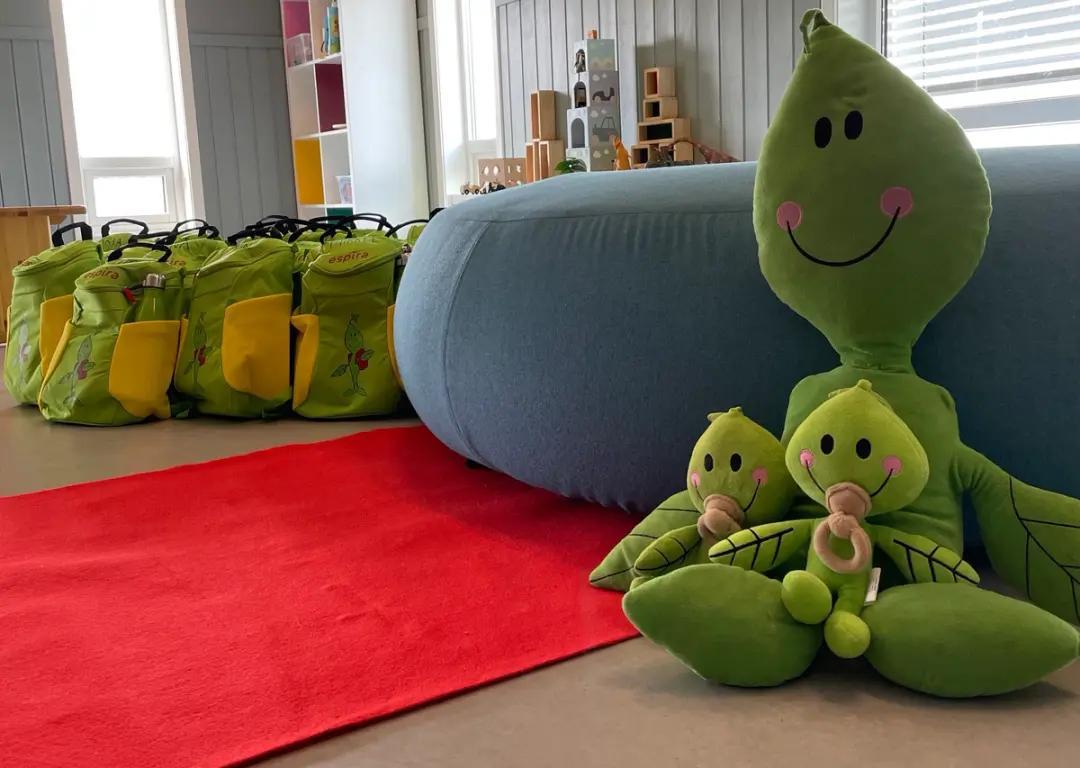 a group of stuffed animals are sitting on a red rug in a room .