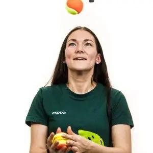 a woman is holding a tennis ball in her hands and throwing it in the air .