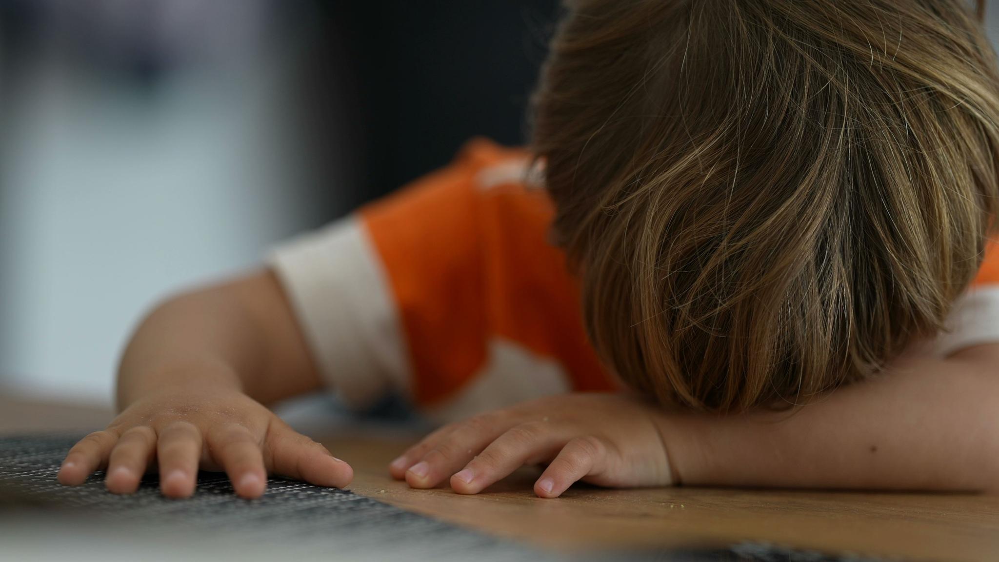 a little boy is laying on the floor with his head down .