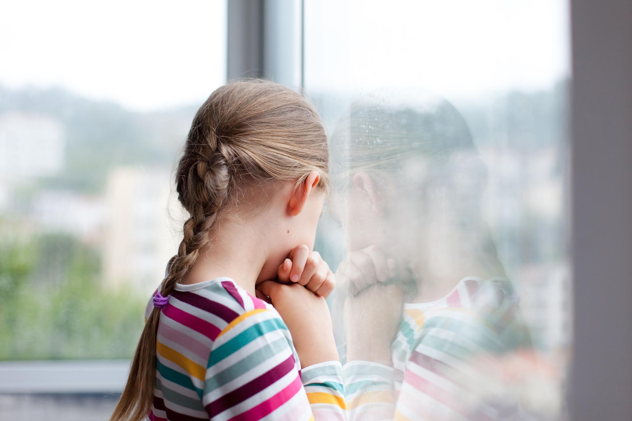 a little girl is looking out of a window .