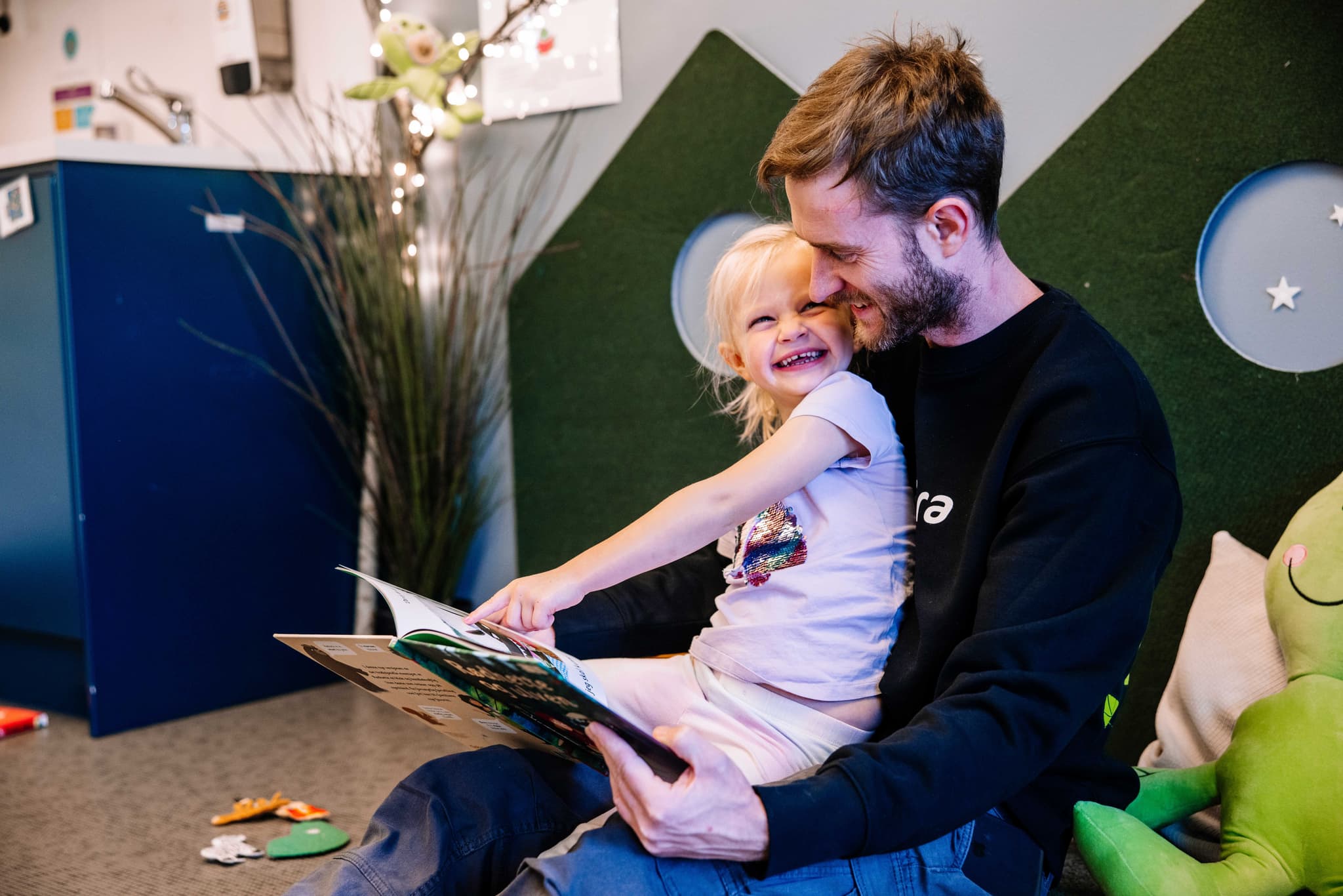 Barnehagebarn leser bok sammen med ansatt i Espira