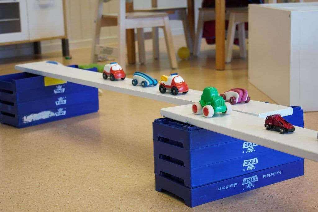 a group of toy cars are sitting on top of a seesaw .