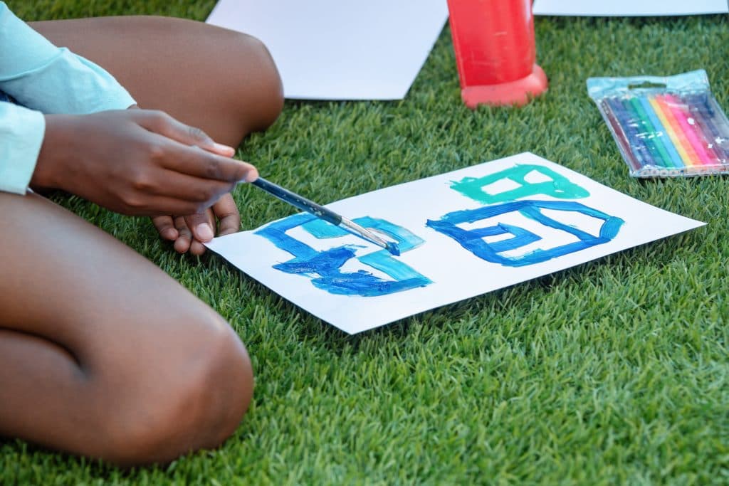 a person is sitting on the grass painting a sign with a brush .