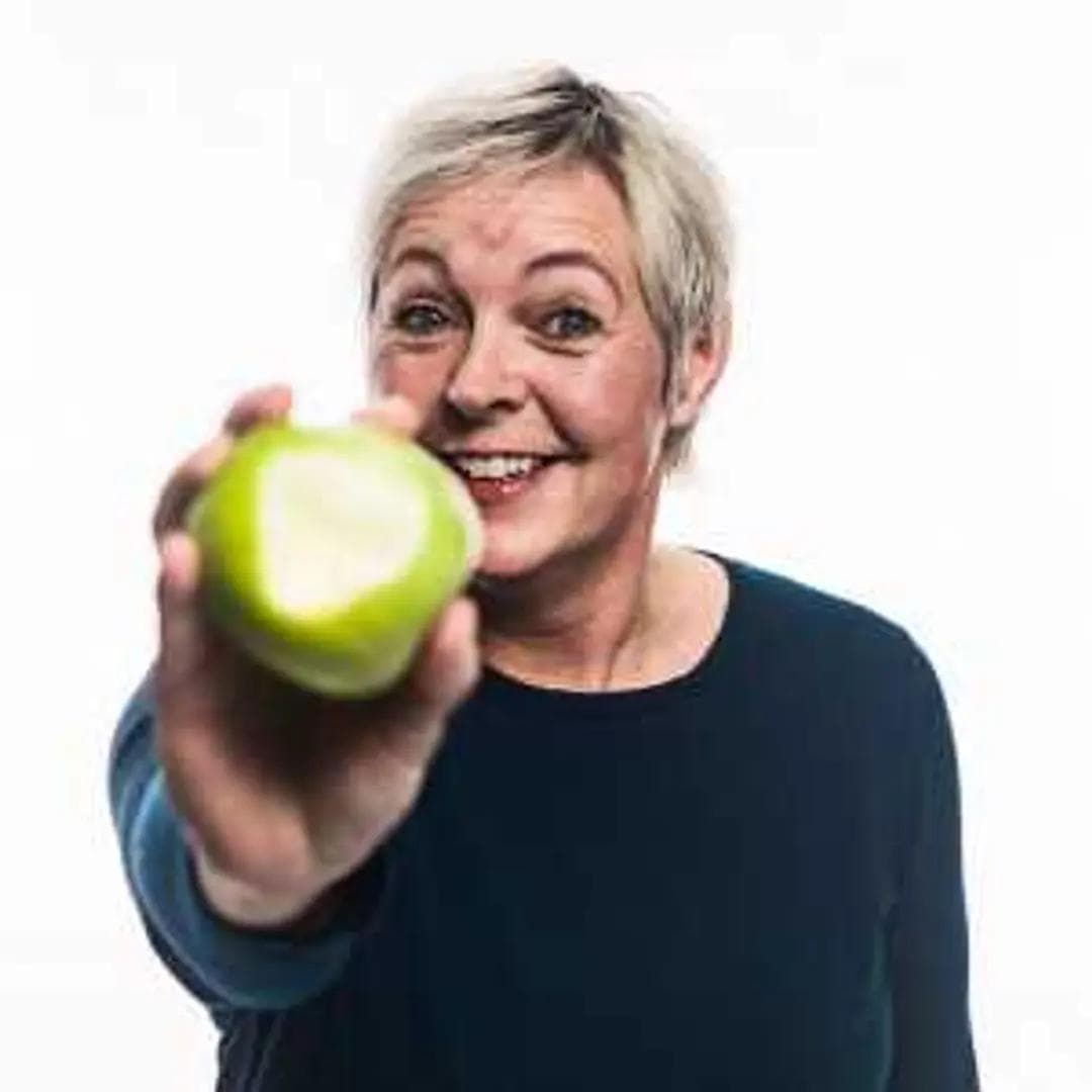 a woman is holding a green apple in her hand and smiling .