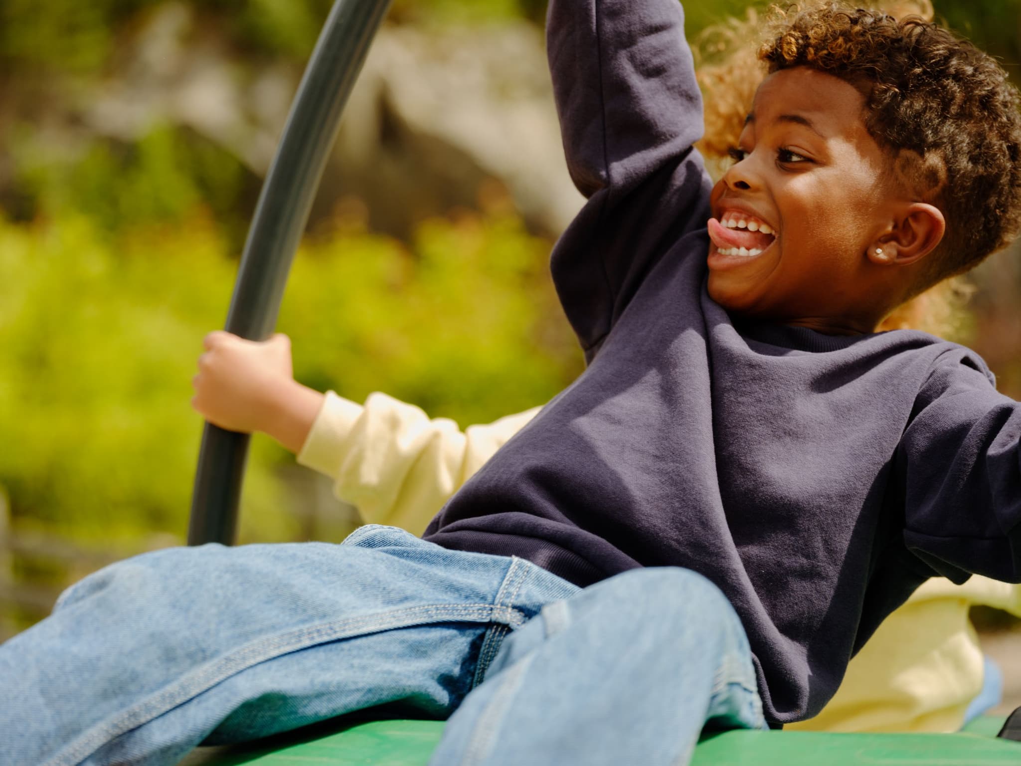a young boy is playing on a green slide at a playground .