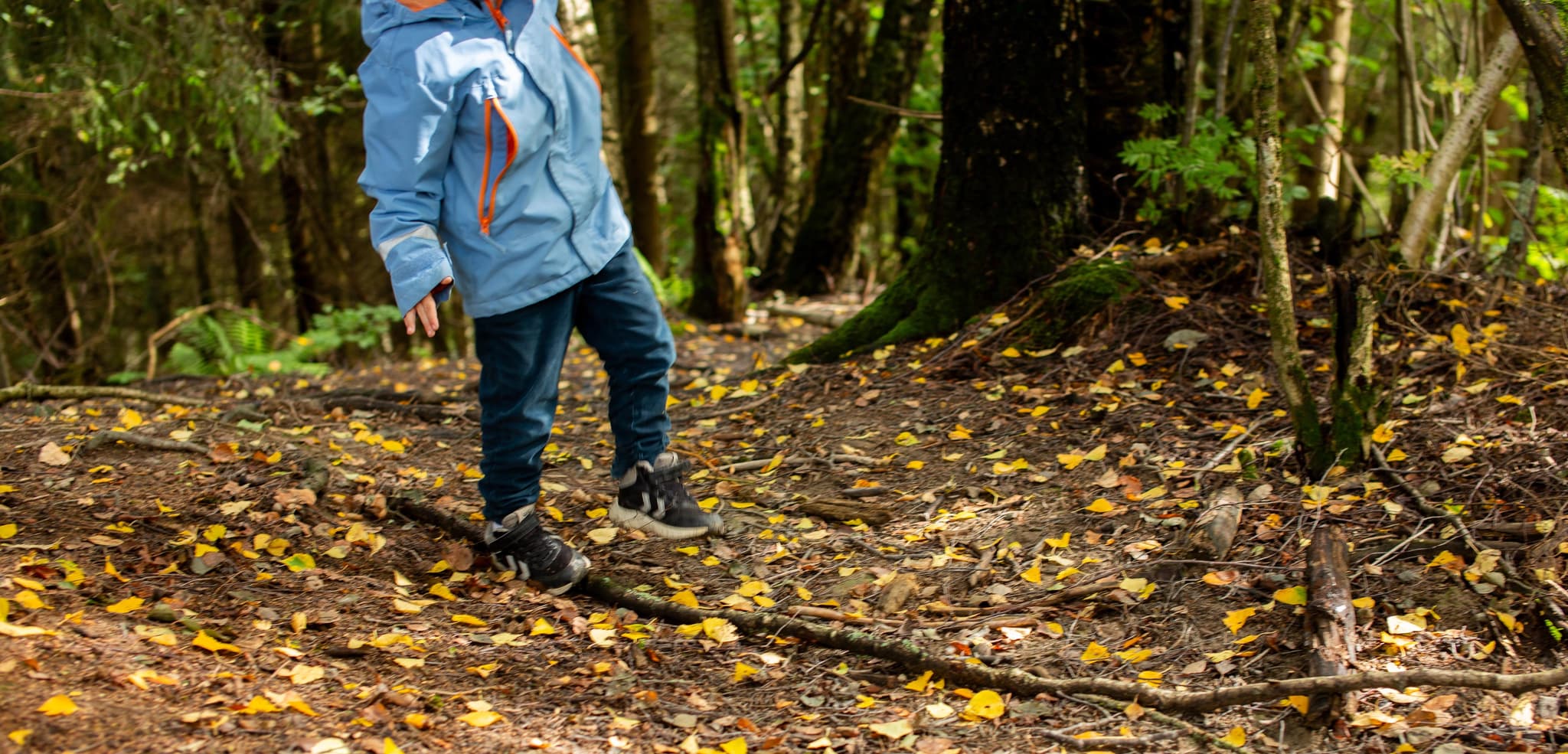 Barn som balanserer på pinne ute i skogen. Espira Barnehage