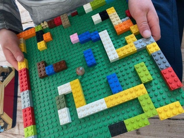 a person is holding a maze made out of lego blocks .