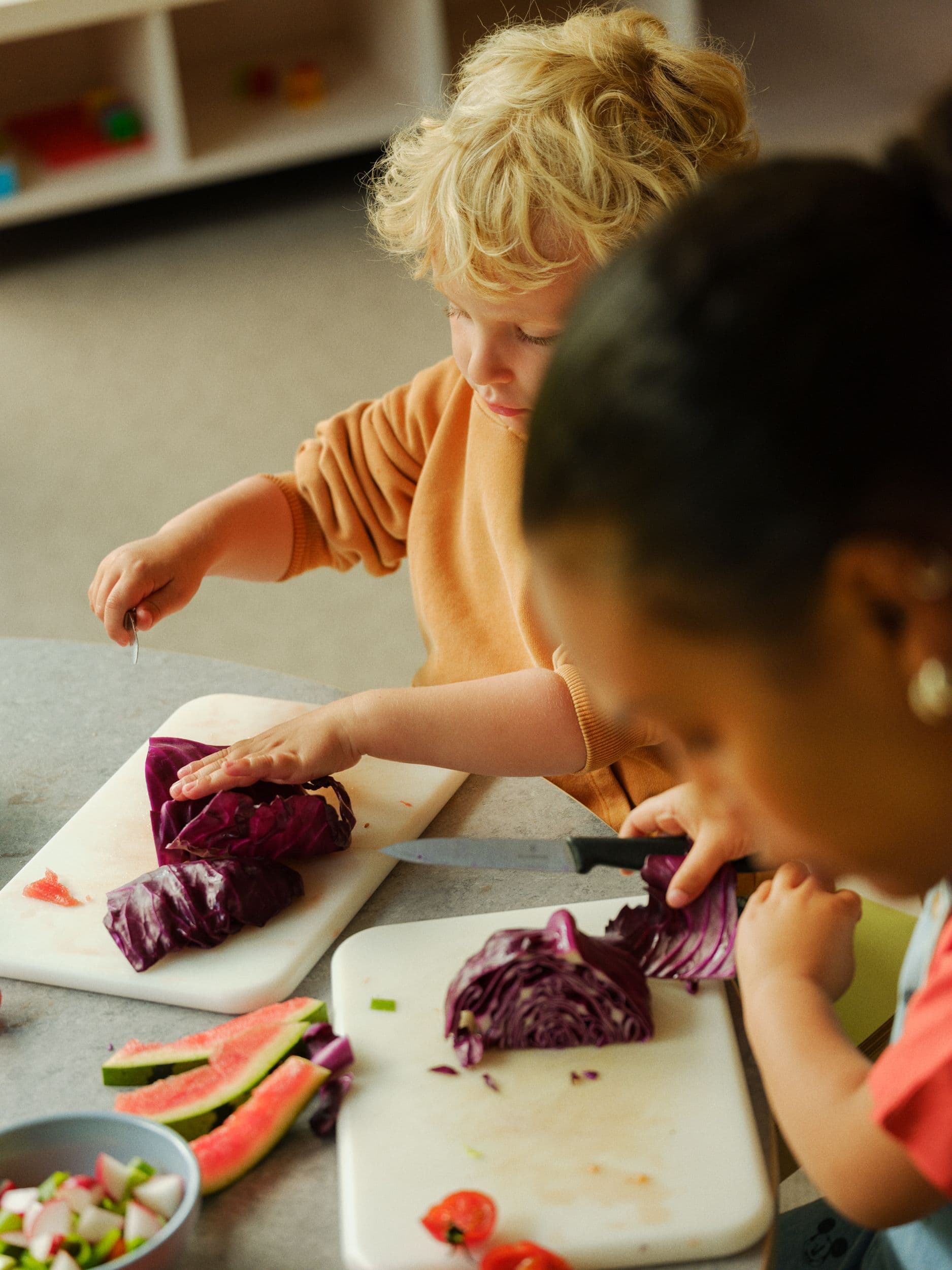 a group of children are cutting vegetables on a cutting board .
