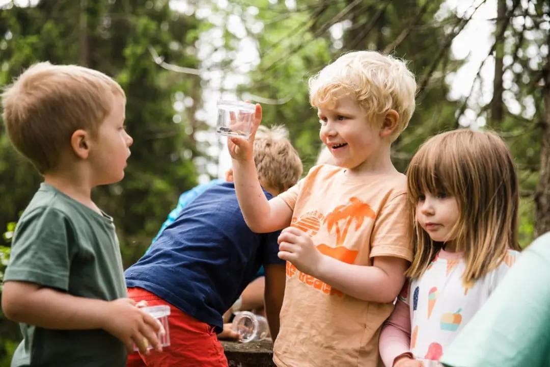 a group of children are standing next to each other in the woods .