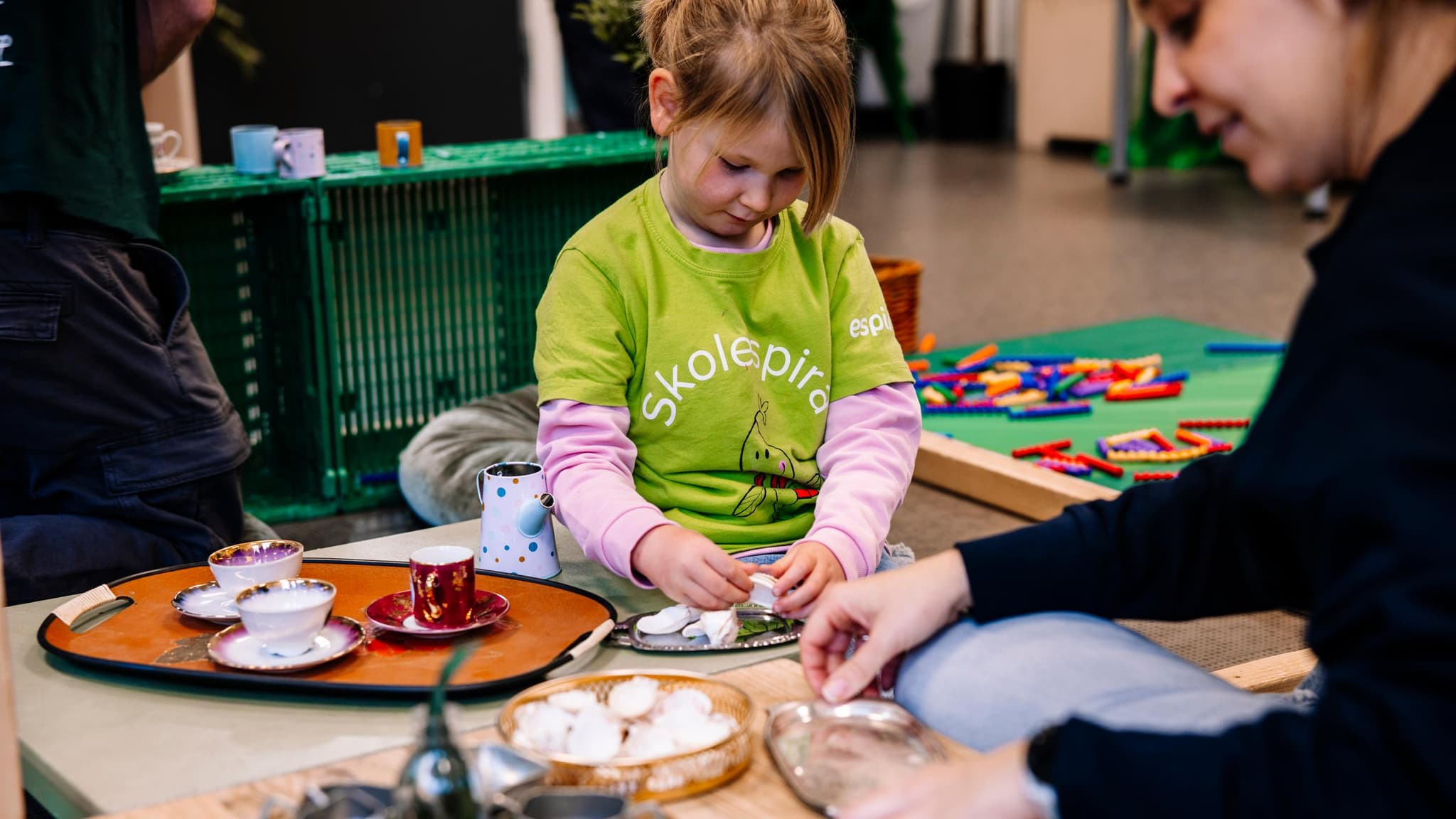 Barn som leker i skolespira-skjorte sammen med ansatt i Espira